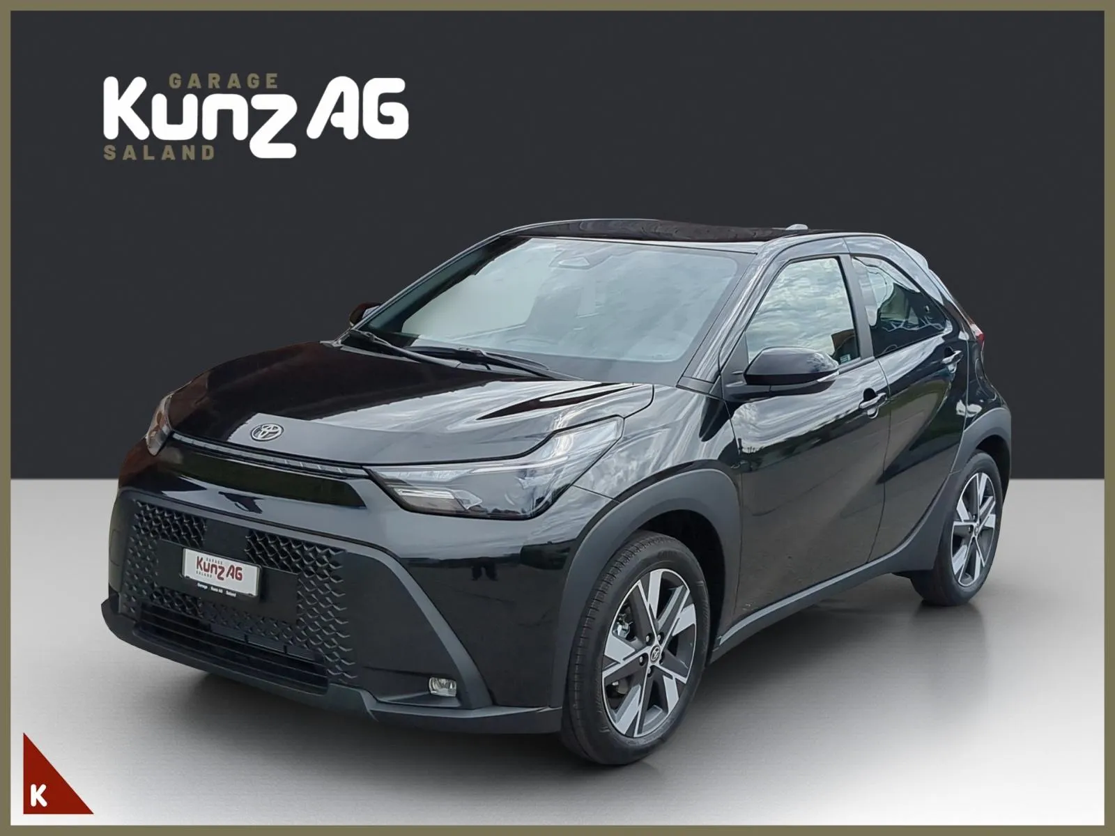 Schrägansicht von vorne links auf einen schwarzen Toyota Aygo X vor dunklem Hintergrund.